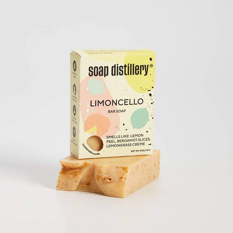 Bar of lemon scented soap with Soap Distillery packaging on a light gray background.
