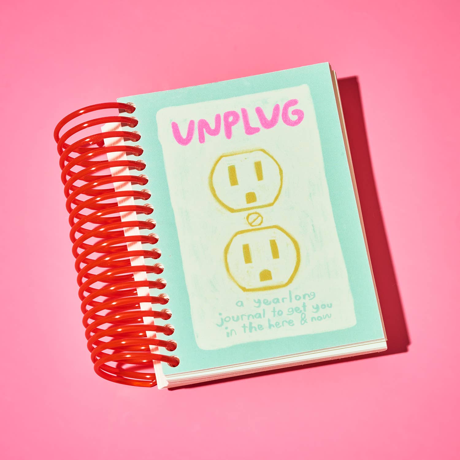 Notebook with 'UNPLUG' text and power outlet design on a pink background.