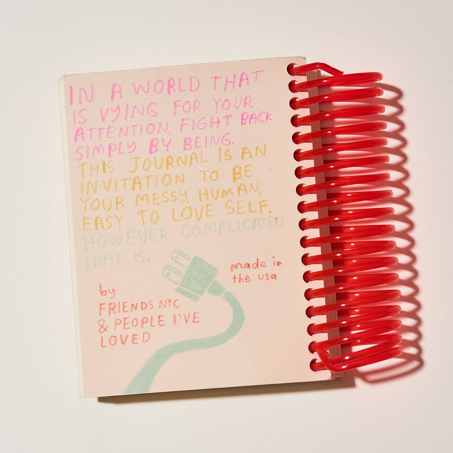 Journal with red spiral binding and motivational text on a white background.